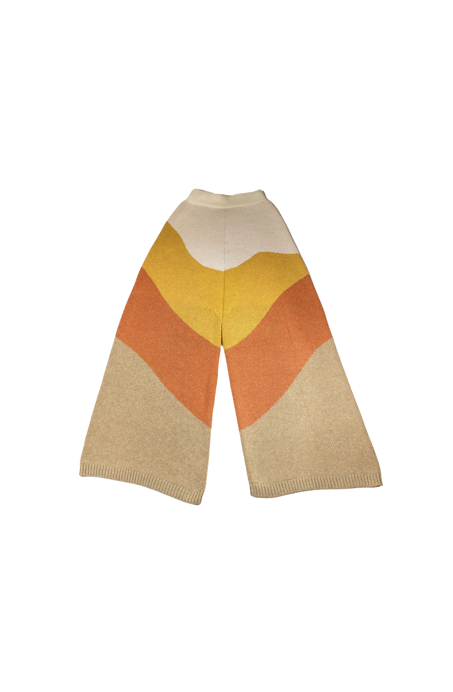 Flat lay of the Luz Jacquard-Knit Pants by My Paloma, showcasing a bold colour block wave design in soft cream, golden mustard, terracotta, and sand tones crafted in a luxurious wide-leg silhouette ideal for upscale city styling.