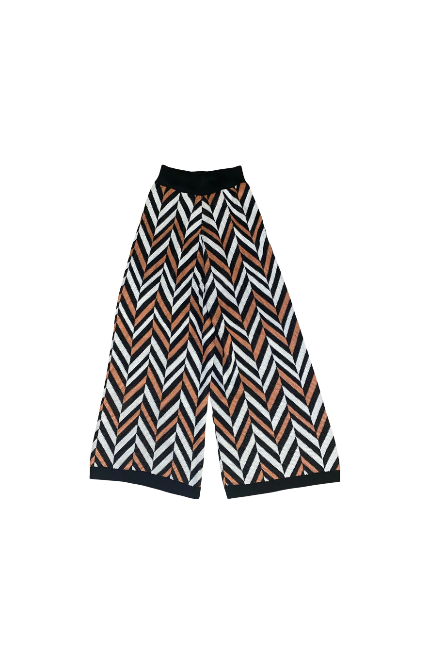 Flat lay of the My Paloma Zig Zag Knit Pants featuring a bold chevron stripe design in black, terracotta, and ivory, with a wide-leg cut and black contrast waistband and hems crafted for standout luxury loungewear.